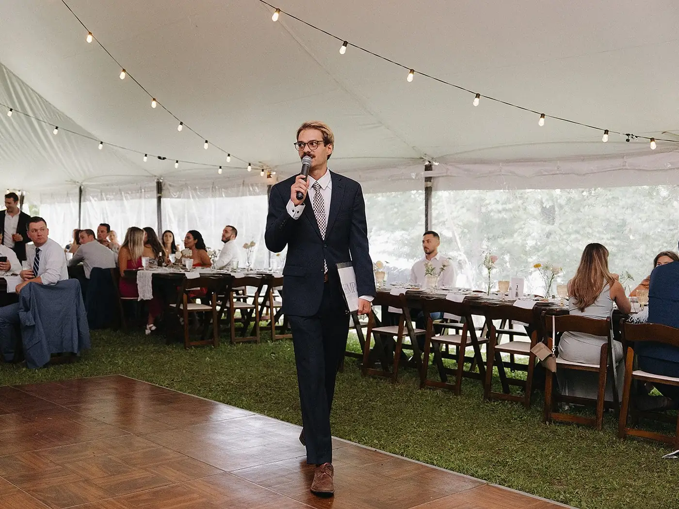 Justin on the microphone at a tented wedding reception