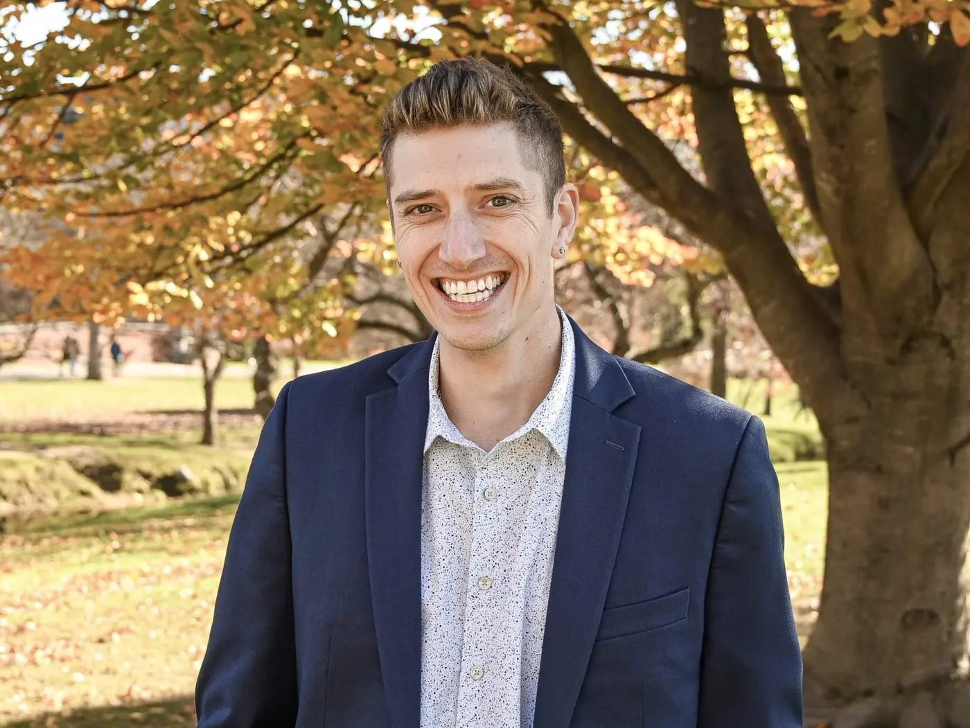Thaddeus smiling in a navy blazer outdoors