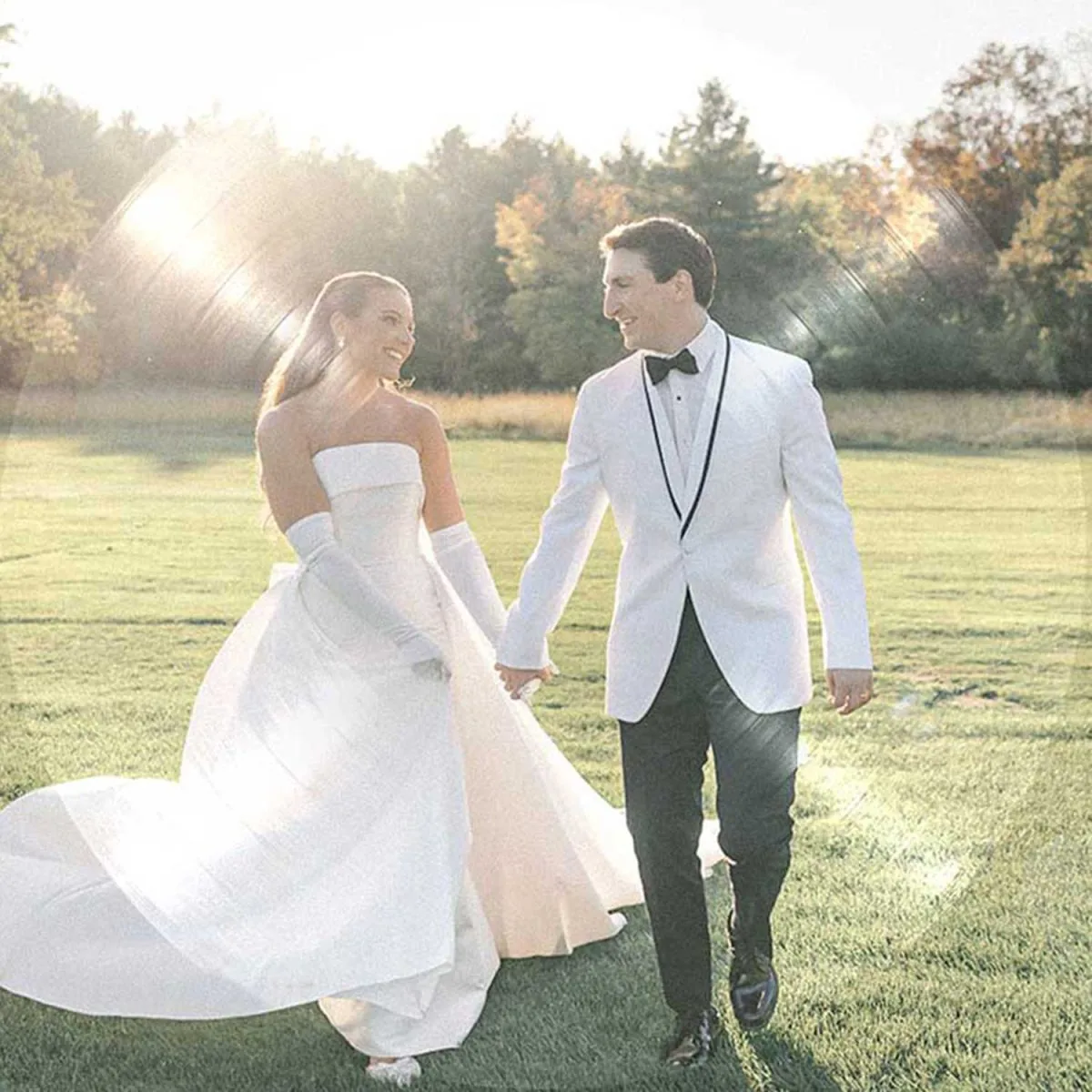 Newlywed couple on a golden hour walk across a scenic field before their reception with VARA DJs.