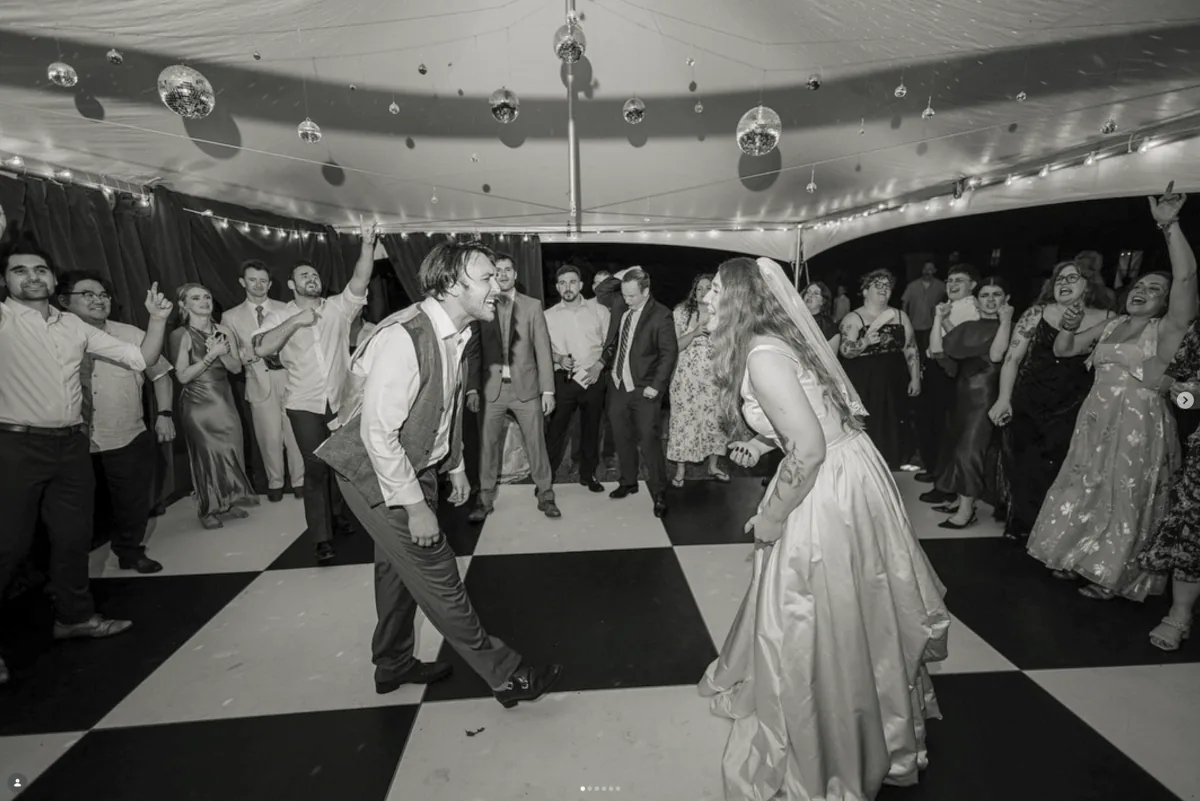 Bride and groom share a last dance on a checkered floor at their wedding reception