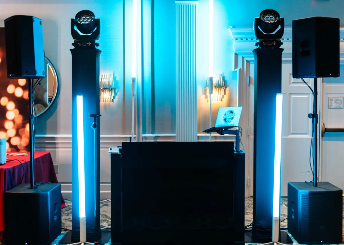 DJ booth between speakers with blue uplighting and lighting fixtures