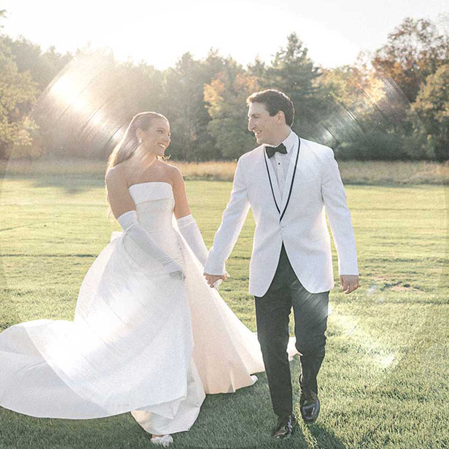 Outdoor Golden Hour Wedding Photography | VARA DJs | Jordynn and Anthony | Albany Country Club Newlywed couple enjoys a golden hour walk across a scenic field, creating timeless wedding memories before their reception with VARA DJs.